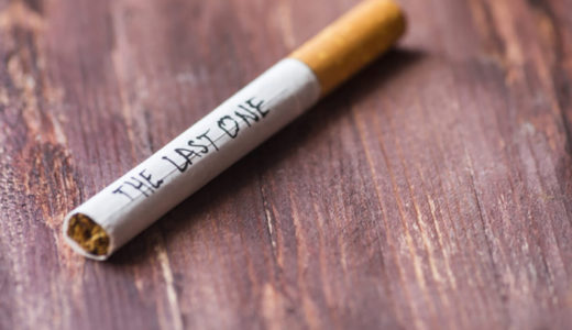 A closeup phot of a wooden table with a cigarette with the words, "the last one" written on the side.
