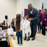 Dr. Bizzell helping present lab coats