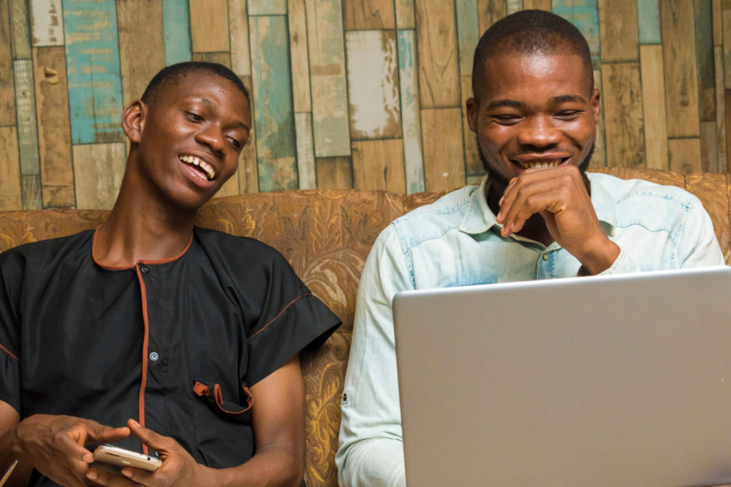 two african young businessmen seriously working with their mobile phone and laptop feeling about what they saw on their device